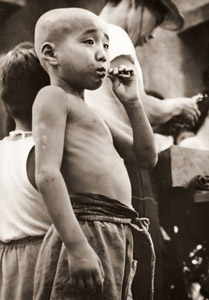 アパート街の人気者(べっこう飴を咥える男の子） [渡辺秀夫, フォトアート 1955年7月号より]のサムネイル画像