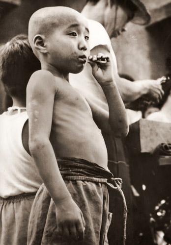 アパート街の人気者(べっこう飴を咥える男の子） [渡辺秀夫, フォトアート 1955年7月号より] パブリックドメイン画像 