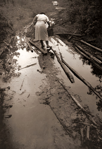 患者の家からの帰り。車までの泥んこ道に苦労するモード・カレン サウスカロライナを舞台にしたフォトエッセイ「助産婦モード・カレン」から [ユージン・スミス, 1951年, 栄光の「LIFE」展 1946-1955 時代の顔を衝くより] パブリックドメイン画像 