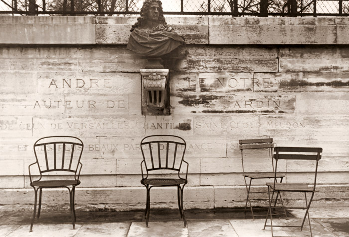 チュイルリー公園の壁の前に置かれた椅子4つ 壁に彫られた文字はチュイルリーなどのフランスの公園を設計したアンドレ・ル・ノートルの業績を記している [ロバート・フランク, 1951年, 栄光の「LIFE」展 1946-1955 時代の顔を衝くより] パブリックドメイン画像 