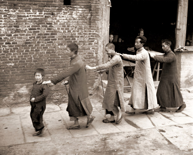 小さな男の子の先導で衡陽の町の通りを歩く目の不自由な人たち この頃中国は飢餓のさなかであった [ジョージ・シルク, 1946年, 栄光の「LIFE」展 1946-1955 時代の顔を衝くより] パブリックドメイン画像 