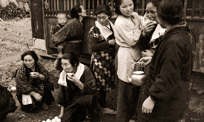 祖母と嫁ぐ孫娘（招かれない嫁見の村人たちにも外で白い酒がふるまわれる） [岩田幸助, 日本カメラ 1956年1月号より] パブリックドメイン画像 