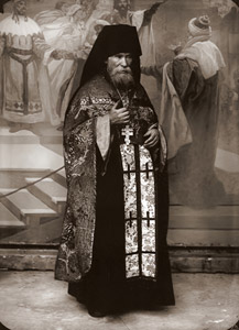 スラヴ叙事詩・第18作「聖アトス山」（1926年）に描写されるギリシャ正教の高僧の衣装をまとったモデル。背後に第12作｢－オタカル2世｣の完成品がみえる。 [アルフォンス・ミュシャ, 1924年頃, 「ミュシャが愛した光と時代」展より]のサムネイル画像