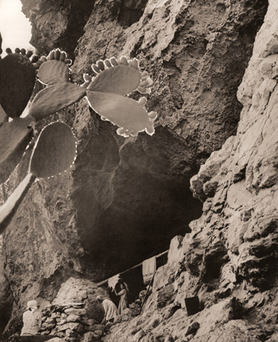秘められた峡谷（寝床に使う獣皮や毛布を干す洞窟と居住者） [ラルフ・クレーン, アサヒカメラ 1952年9月号より] パブリックドメイン画像 