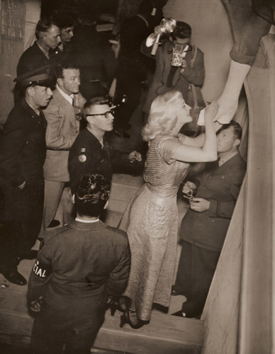 会場でアメリカ将兵の繃帯した脚に、乞われるままサインするマックスウェル [稲村隆正, アサヒカメラ 1951年1月号より] パブリックドメイン画像 
